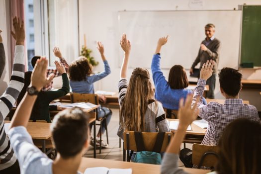 Teens-with-hands-up-in-class